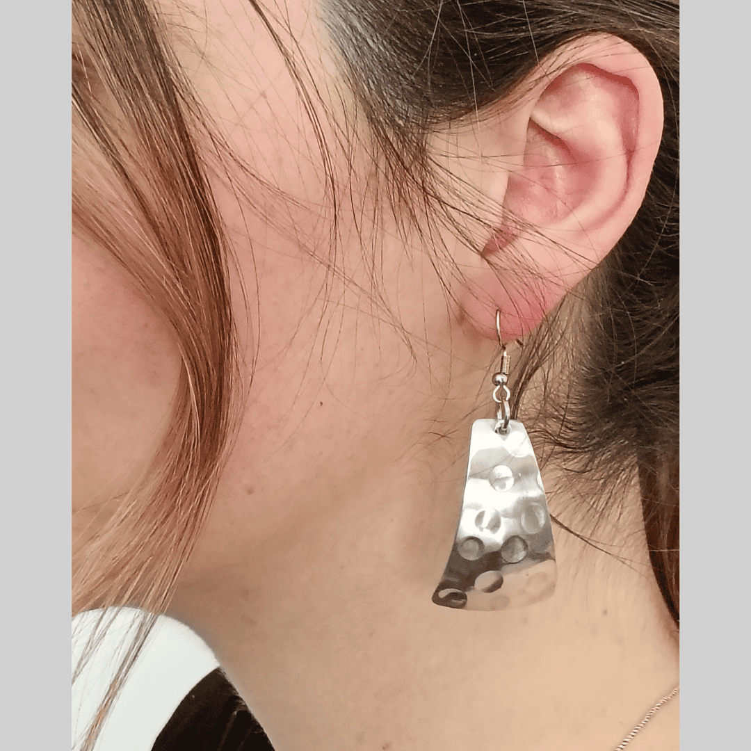 Silver earrings worn by a person with brown hair.