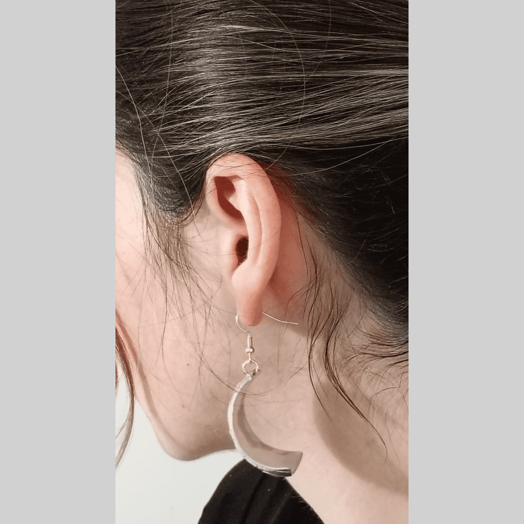 Close-up of an ear wearing a silver hoop earring with a neutral background