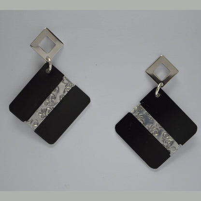 A pair of square earrings with matte black anodized aluminum and polished aluminum accents with embossed detailing.
