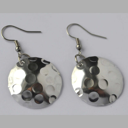 A pair of silver disc-shaped earrings with a hand-hammered texture and circular pattern design.