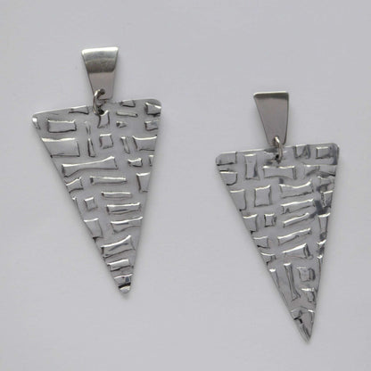 A pair of silver triangle earrings with a textured, artisanal stone-print pattern.